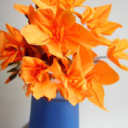 A blue vase holding orange origami flowers
